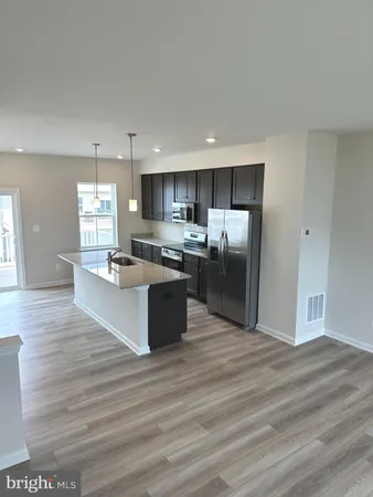 a large kitchen with kitchen island a sink dishwasher a refrigerator and wooden floor