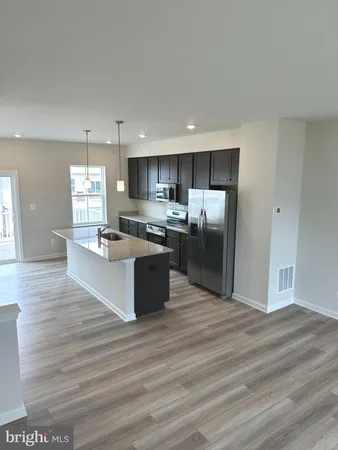 a large kitchen with kitchen island a sink dishwasher a refrigerator and wooden floor
