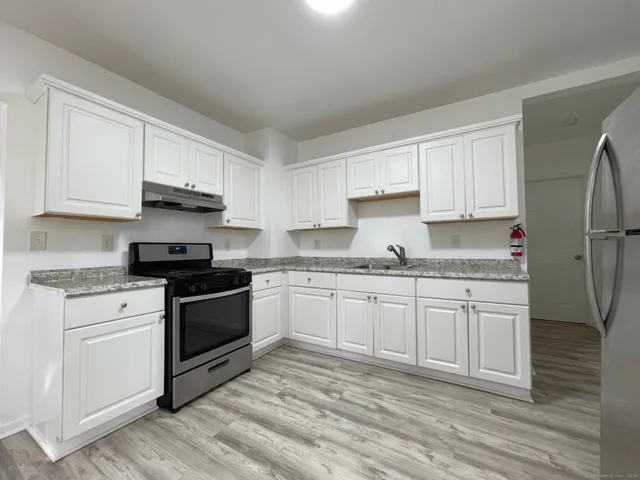 a kitchen with granite countertop white cabinets and white appliances