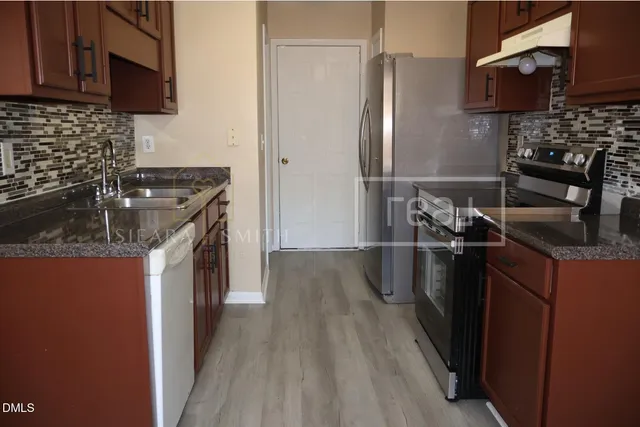 a kitchen with granite countertop a sink stove and refrigerator