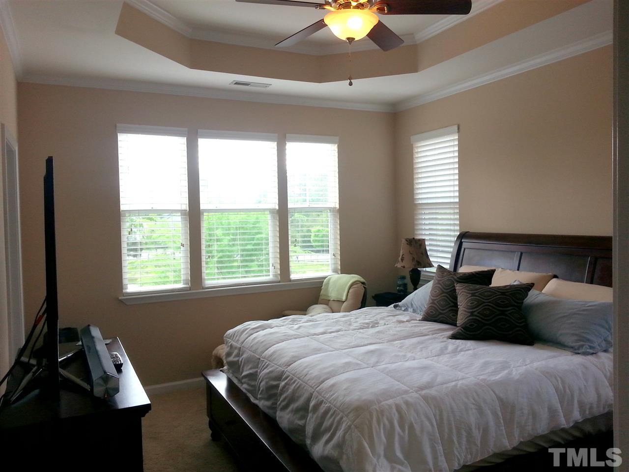 10131 Lynnberry Place Raleigh, NC 27617 - Photo 18 of 25 Spacious master bedroom features triple windows along the back of the home overlooking a peaceful pond. Large walk in closet, tray ceiling, crown molding and ceiling fan.