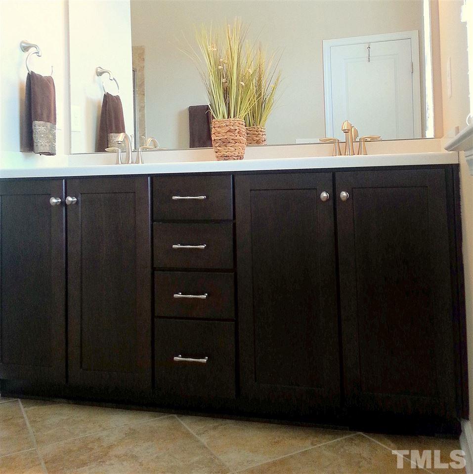 10131 Lynnberry Place Raleigh, NC 27617 - Photo 21 of 25 Upgraded bathroom cabinets and drawer stack accented with brushed nickle knobs and pulls. Smooth-surface Corian countertops with a raised double-bowl vanity. Linen storage closet and enlongated toilet for comfort.