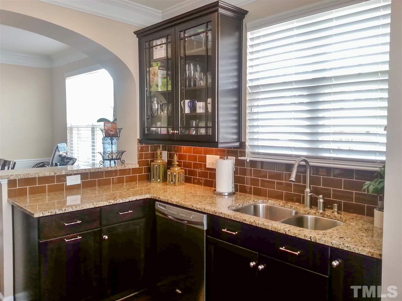 10131 Lynnberry Place Raleigh, NC 27617 - Photo 8 of 25 A chef's dream! Functional kitchen w/plenty of countertop space, glass subway tile backsplash, 42" cabinets w/crown molding, glass doors, under-cabinet lights, roll-out shelves, pull-out trash/recycling, deep SS sink, Moen faucet w/pull out sprayer.
