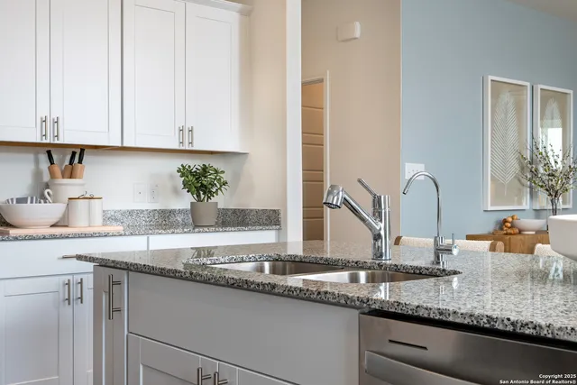 a kitchen with granite countertop a sink and white cabinets