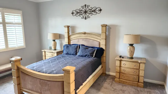 a bed sitting in a bedroom next to a window with a lamp