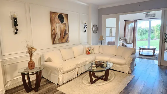 a living room with furniture a wooden floor and large window