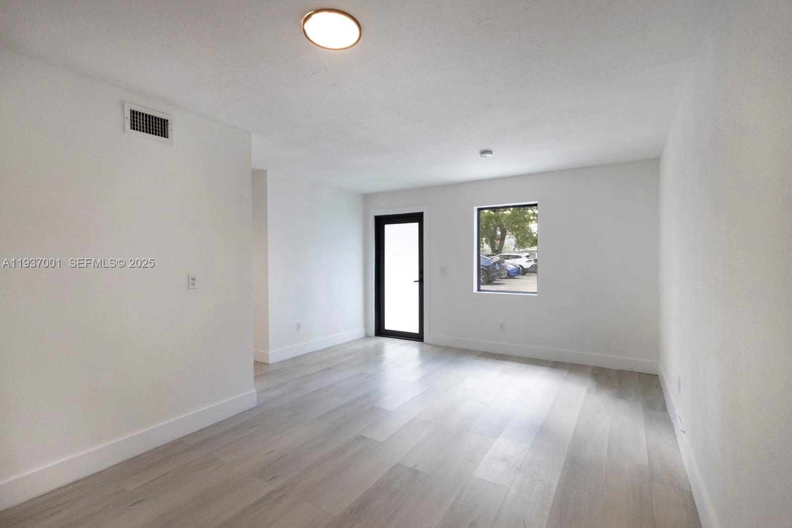 37 Northwest 59th Street, Unit 7 Miami, FL 33127 - Photo 4 of 15 an empty room with wooden floor and windows