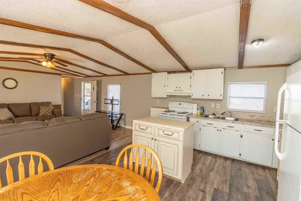 a kitchen with stainless steel appliances granite countertop a stove a sink dishwasher and white cabinets with wooden floor