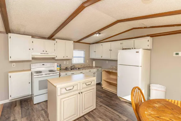a kitchen with cabinets appliances wooden floor and a window