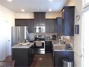 a kitchen with kitchen island granite countertop a sink stove refrigerator and cabinets