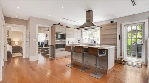 a kitchen with stainless steel appliances kitchen island granite countertop a table chairs sink and cabinets