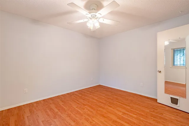 a view of a big room with wooden floor and a chandelier fan