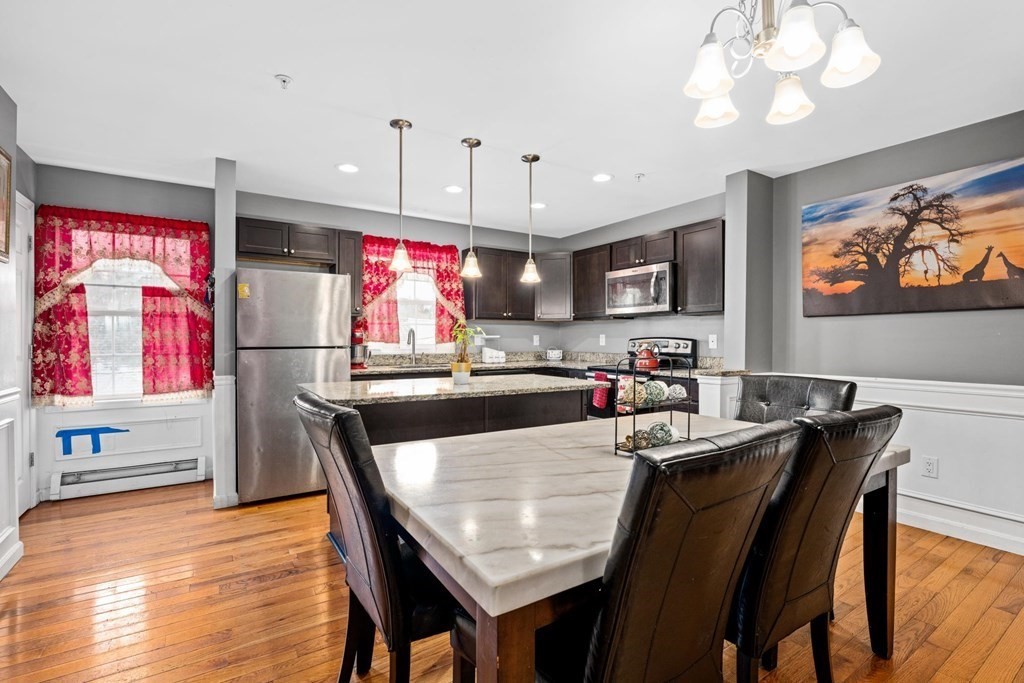 7 South Maxwell Court Worcester, MA 01607 - Photo 8 of 19 a kitchen with stainless steel appliances granite countertop a refrigerator a microwave a stove and a dining table with wooden floor