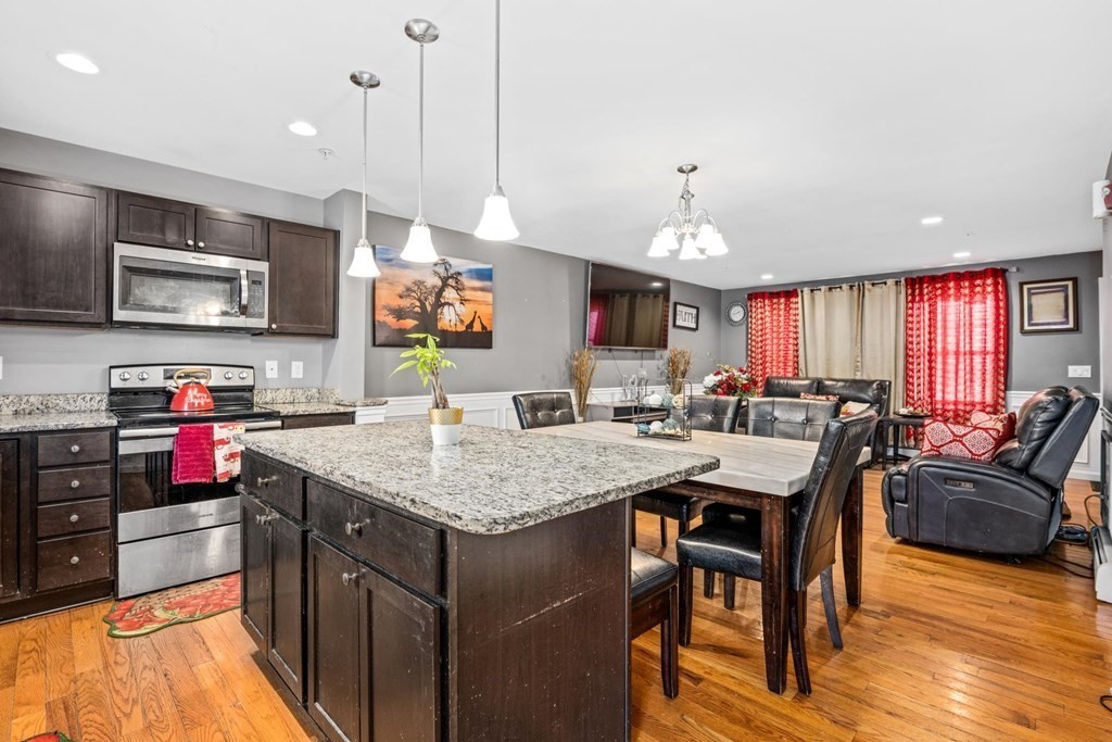 7 South Maxwell Court Worcester, MA 01607 - Photo 10 of 19 a kitchen with stainless steel appliances granite countertop a stove top oven a sink dishwasher a dining table and chairs with wooden floor