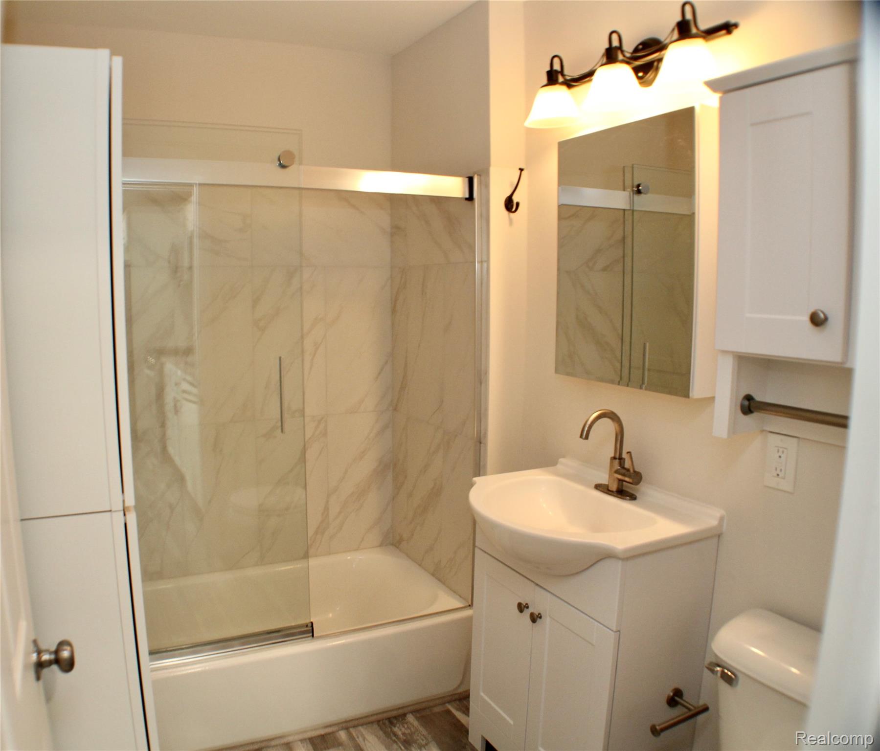 48677 Sugarbush Road, Unit 1 New Baltimore, MI 48047 - Photo 9 of 10 Bathroom featuring a white vanity with integrated sink, brushed bronze-finish faucet, and a wall-mounted medicine cabinet