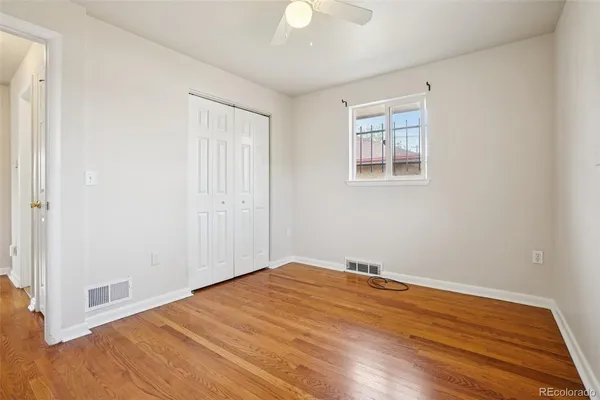 a view of empty room with wooden floor and fan