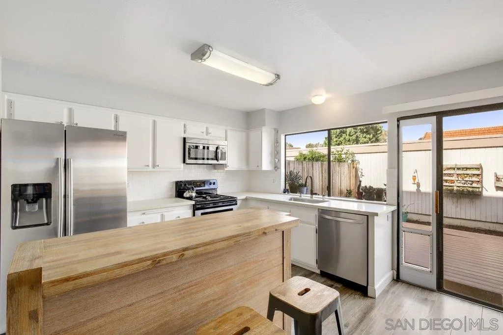 2807 Via Pajaro Carlsbad, CA 92010 - Photo 7 of 26 a kitchen with stainless steel appliances granite countertop a refrigerator a sink a stove and white cabinets with wooden floor