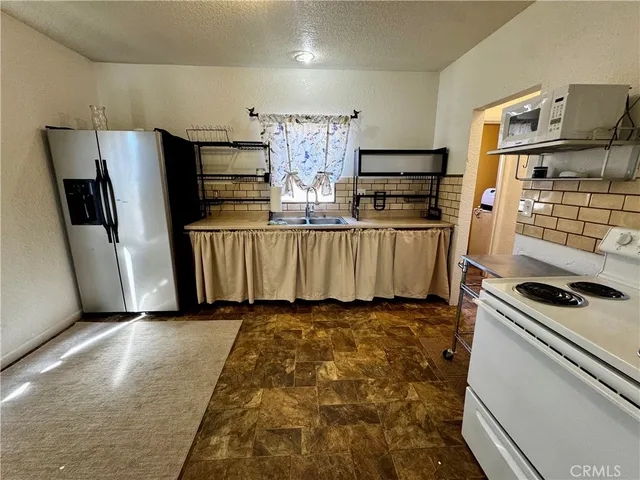 a kitchen with stainless steel appliances granite countertop a refrigerator a stove and a sink