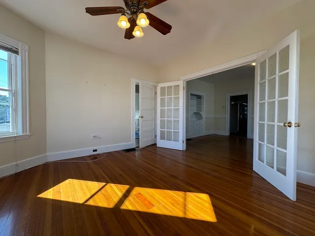 a view of a room with wooden floor and ceiling fan
