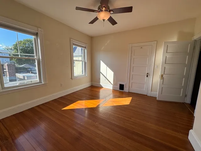 a view of empty room with wooden floor and fan