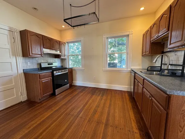 a kitchen with stainless steel appliances granite countertop wooden floors a stove and a sink
