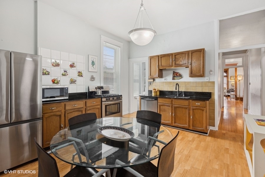 Undisclosed Address Chicago, IL 60657 - Photo 20 of 40 a kitchen with stainless steel appliances kitchen island granite countertop a dining table and chairs