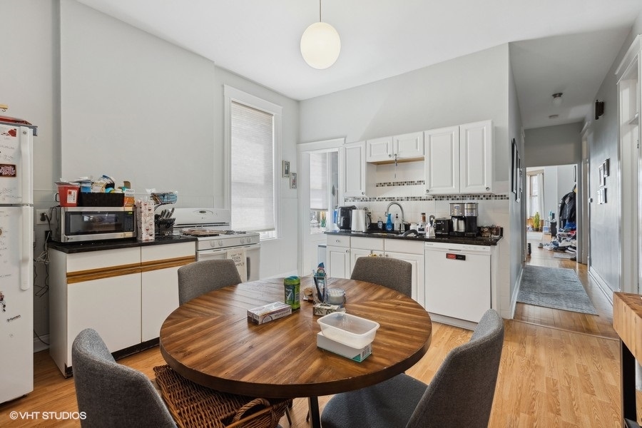 Undisclosed Address Chicago, IL 60657 - Photo 27 of 40 a kitchen with white cabinets stainless steel appliances and dining table