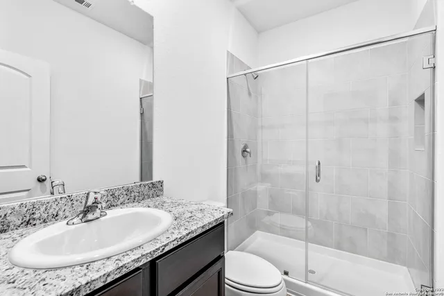 a bathroom with a granite countertop sink a toilet and shower