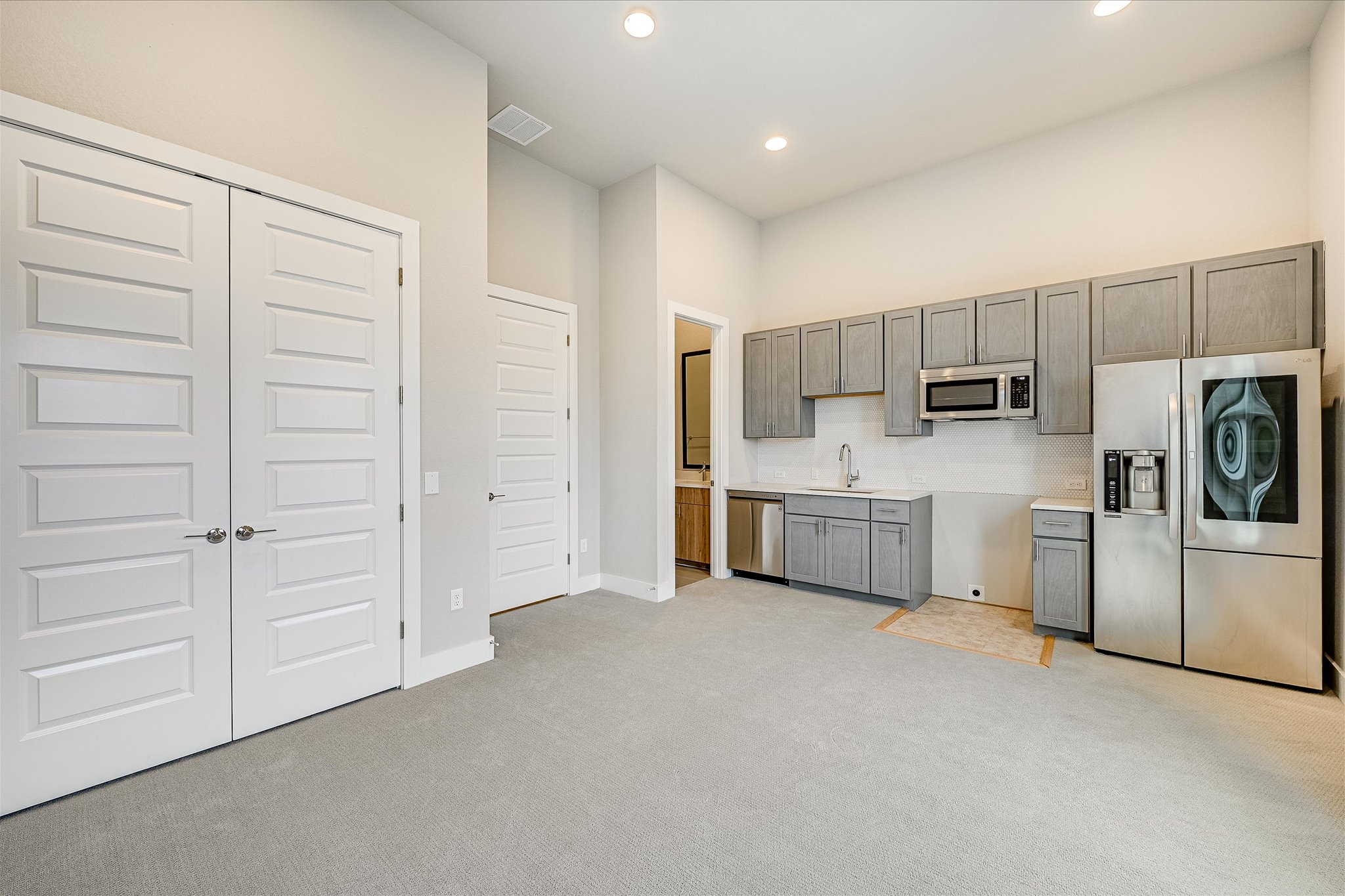6136 Florencia Lane Austin, TX 78724 - Photo 20 of 40 Kitchen with stainless steel appliances, light carpet, a high ceiling, light countertops, and recessed lighting