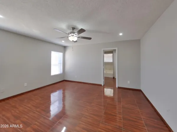 a view of an empty room with wooden floor and a ceiling fan