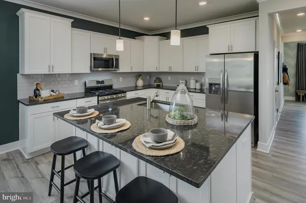 a kitchen with stainless steel appliances granite countertop a sink a stove a kitchen island and chairs with wooden floor