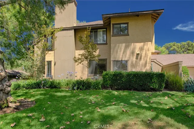 a view of a house with brick walls and a yard with plants