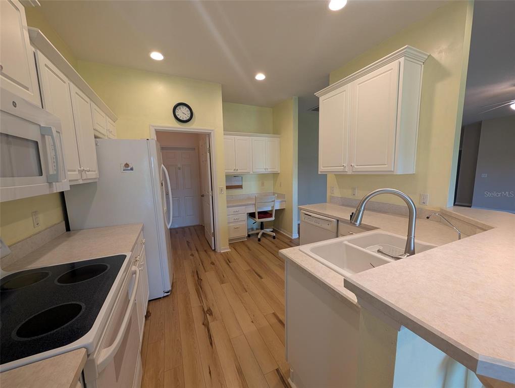 4124 Muirfield Loop Lake Wales, FL 33859 - Photo 15 of 29 a kitchen with stainless steel appliances a stove a sink a refrigerator and wooden cabinets with wooden floor