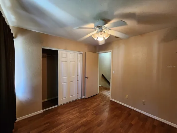 an empty room with wooden floor and fan