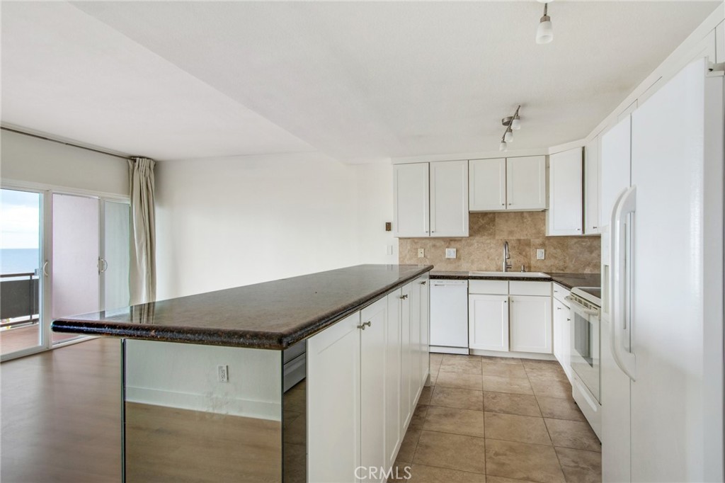 330 Cliff Drive, Unit 308 Laguna Beach, CA 92651 - Photo 10 of 16 a kitchen with a refrigerator and white cabinets