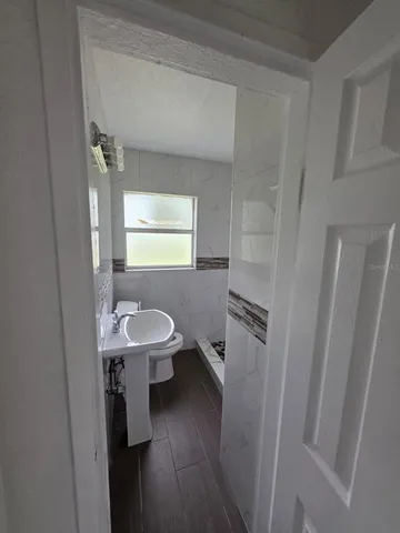 a bathroom with a sink a toilet a window and vanity