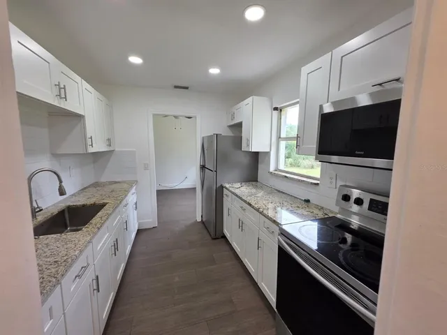 a kitchen with granite countertop a sink and steel appliances
