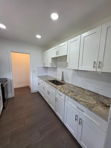 a kitchen with granite countertop white cabinets and stainless steel appliances