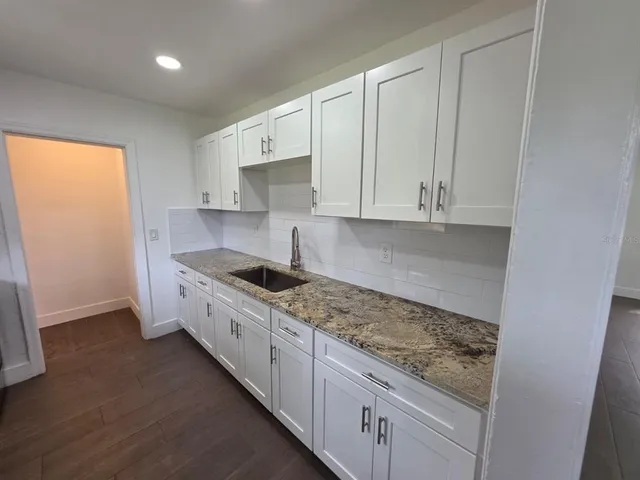 a kitchen with granite countertop white cabinets and a stove