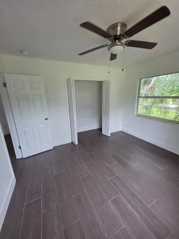 en empty room with wooden floor fan and windows