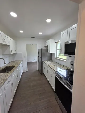 a large kitchen with stainless steel appliances granite countertop a stove a sink and a refrigerator