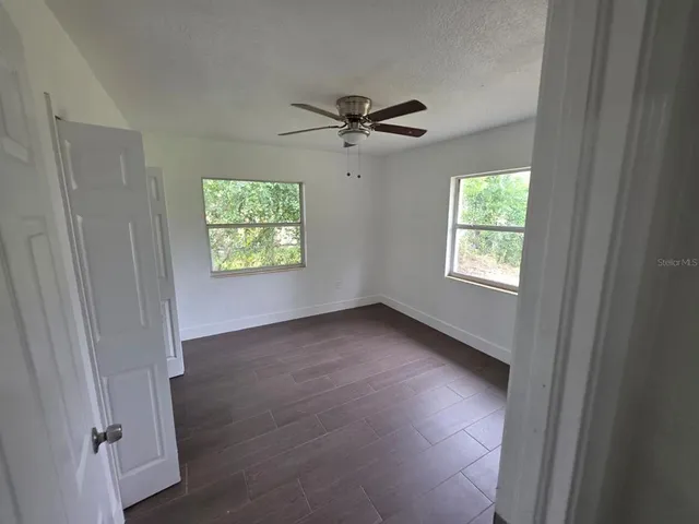 an empty room with windows and fan