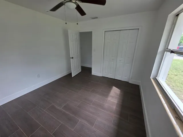 an empty room with windows and fan