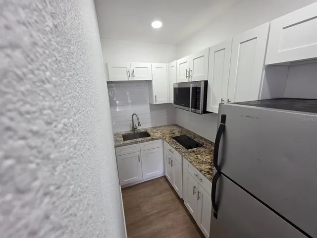 a kitchen with stainless steel appliances granite countertop a stove top oven a sink and a refrigerator