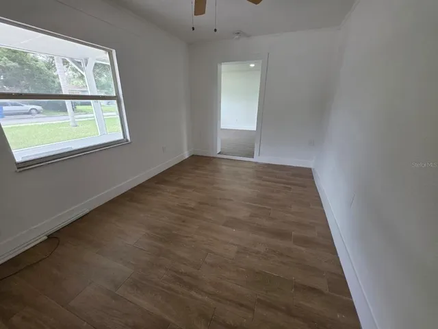 an empty room with wooden floor and windows