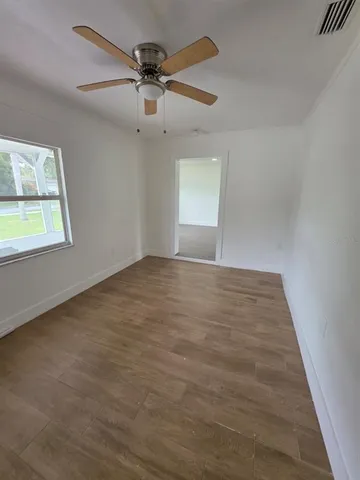 an empty room with windows and fan