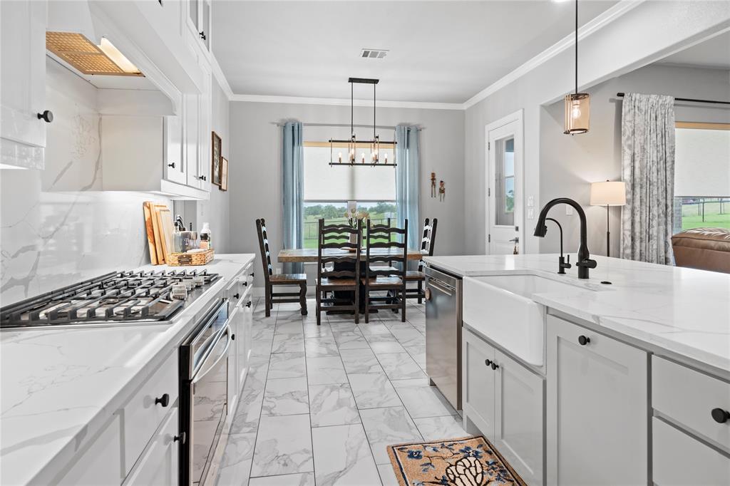 1024 Henry Way Springtown, TX 76082 - Photo 12 of 29 Contemporary kitchen featuring white cabinetry, a gas range with a tile backsplash, white countertops, a large island with an apron-front sink, and matte black fixtures