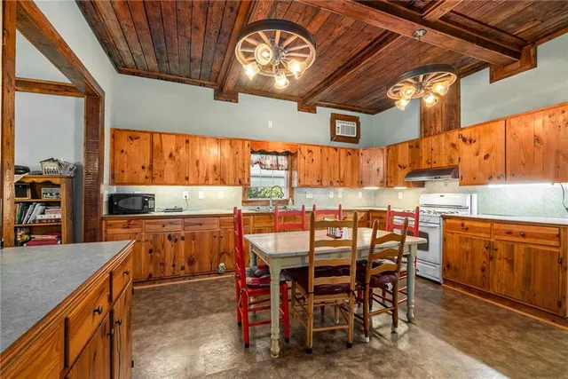 a kitchen with stainless steel appliances granite countertop a table chairs sink and cabinets