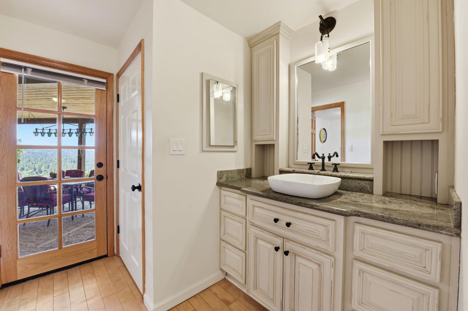 7201 Happy Valley Road Somerset, CA 95684 - Photo 28 of 75 The primary bathroom has a lovely green granite countertop and a basin sink. There is also a glass front door leading to the outside covered patio.