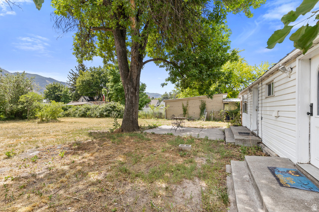 148 South 300 East Logan, UT 84321 - Photo 20 of 29 Expansive backyard featuring a mature tree, concrete patio, and mountain backdrop